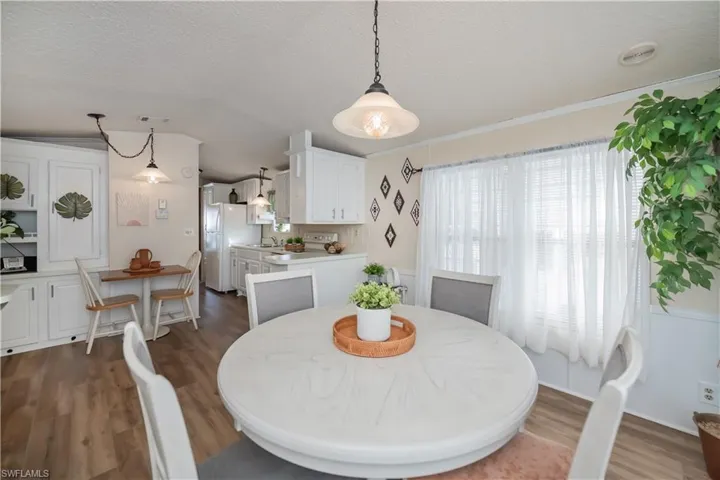 Dining space with a textured ceiling, dark wood-style floors, crown molding, and vaulted ceiling