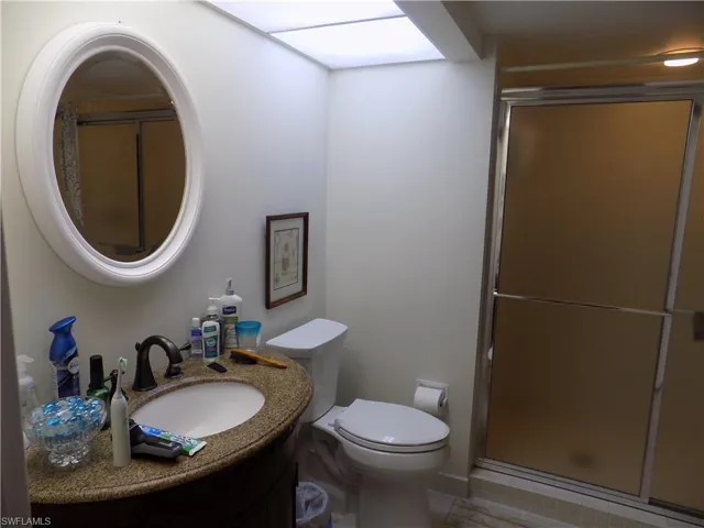 Bathroom with vanity, a shower stall, toilet, and tile patterned floors