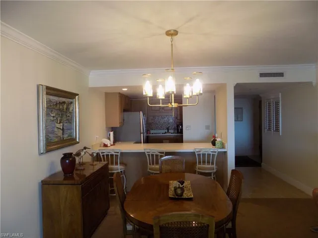 Tiled dining room with a chandelier, crown molding, a sink, and baseboards