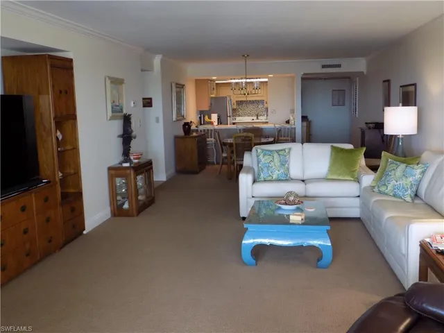 Living room featuring carpet flooring, ornamental molding, and baseboards