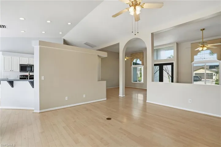 Unfurnished living room featuring a ceiling fan, light wood-type flooring, arched walkways, recessed lighting, and lofted ceiling