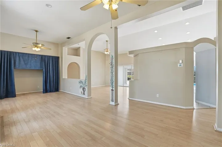 Unfurnished living room featuring arched walkways, light wood finished floors, recessed lighting, and ceiling fan