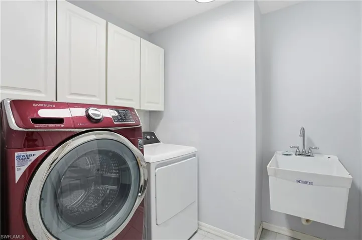 Washroom featuring cabinet space, independent washer and dryer, and light tile patterned floors