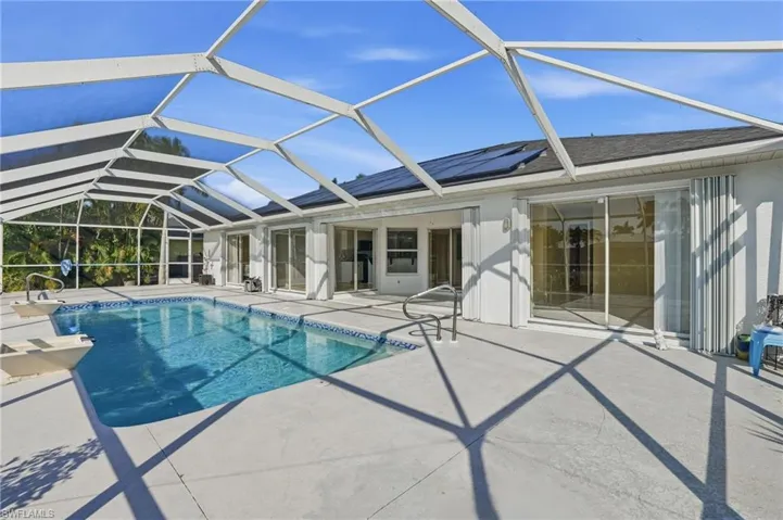 Outdoor pool featuring glass enclosure, a sunroom, and a patio