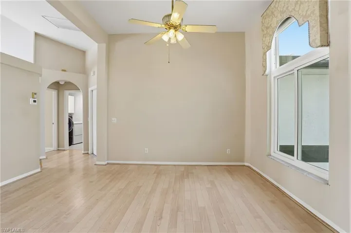 Spare room with arched walkways, light wood finished floors, a ceiling fan, and washer / clothes dryer