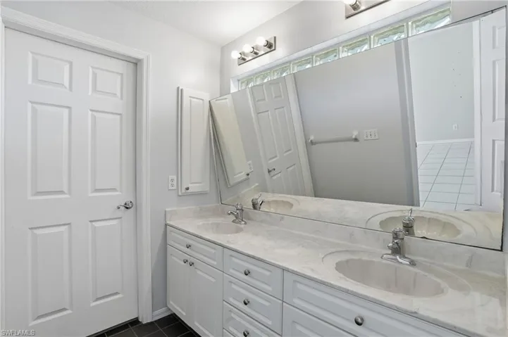 Full bathroom with dark tile patterned floors and double vanity
