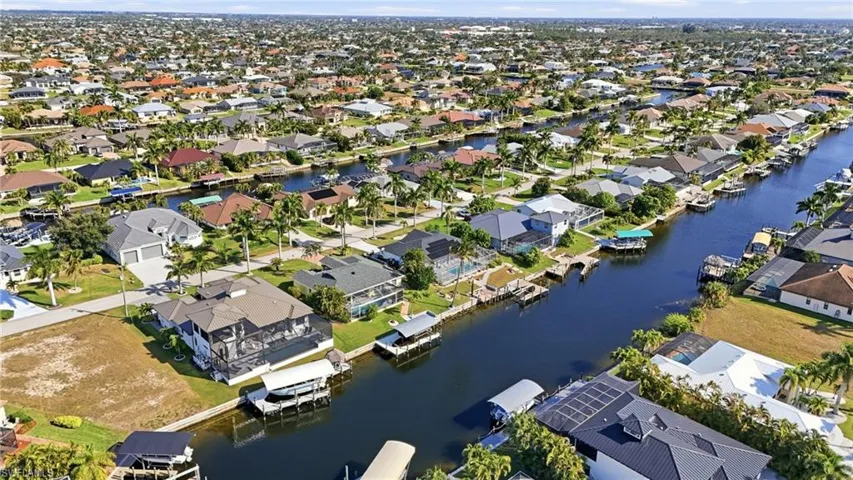 Aerial view of property and surrounding area featuring nearby suburban area and a nearby body of water