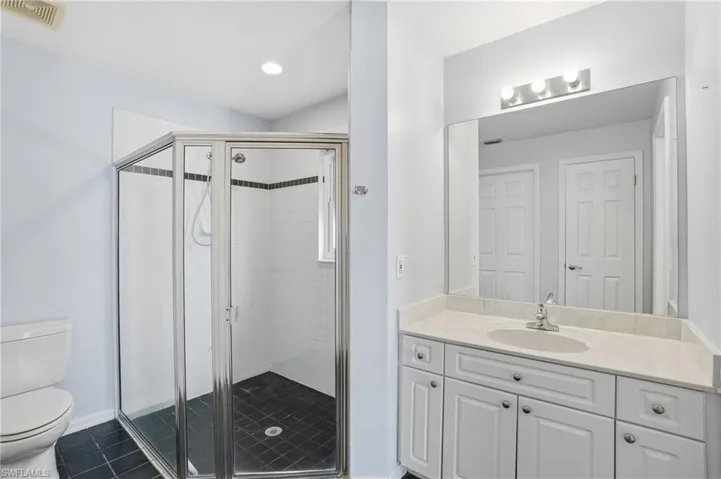 Bathroom featuring vanity, a shower stall, dark tile patterned flooring, and recessed lighting