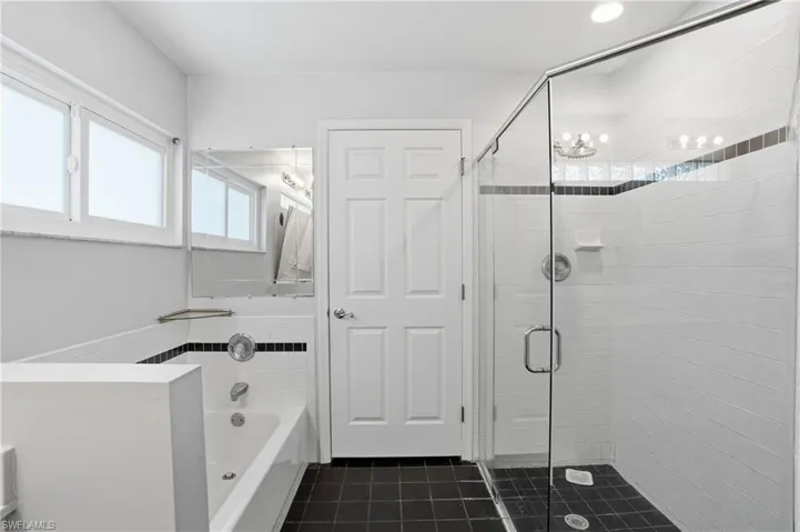 Full bath with a bath, a stall shower, and dark tile patterned flooring