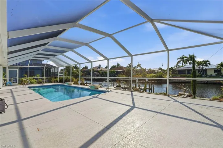 Outdoor pool with glass enclosure, a sunroom, a water view, and a patio