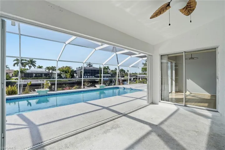 Outdoor pool with glass enclosure, a sunroom, and a patio
