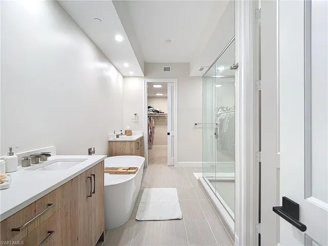 Bathroom featuring vanity, shower with separate bathtub, and tile patterned floors