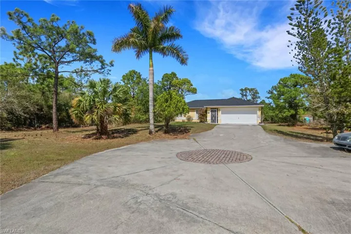 View of front of property featuring curved driveway, a front lawn, and a garage