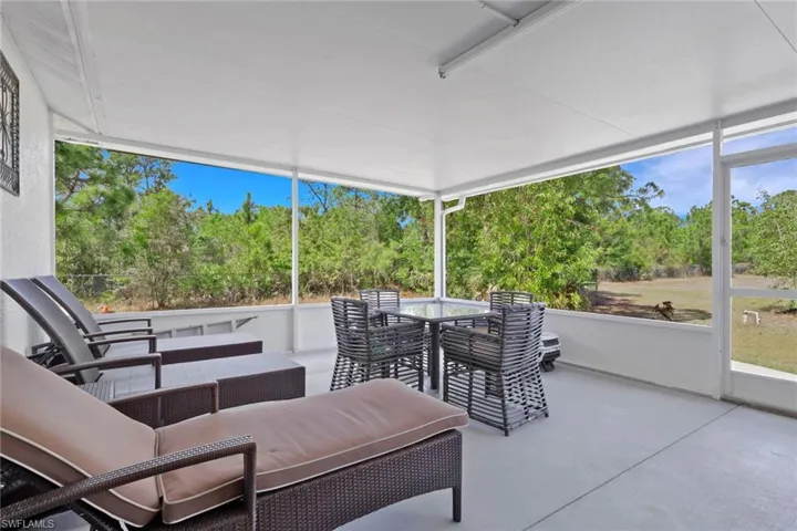 Sunroom / solarium featuring outdoor dining space and view of scattered trees