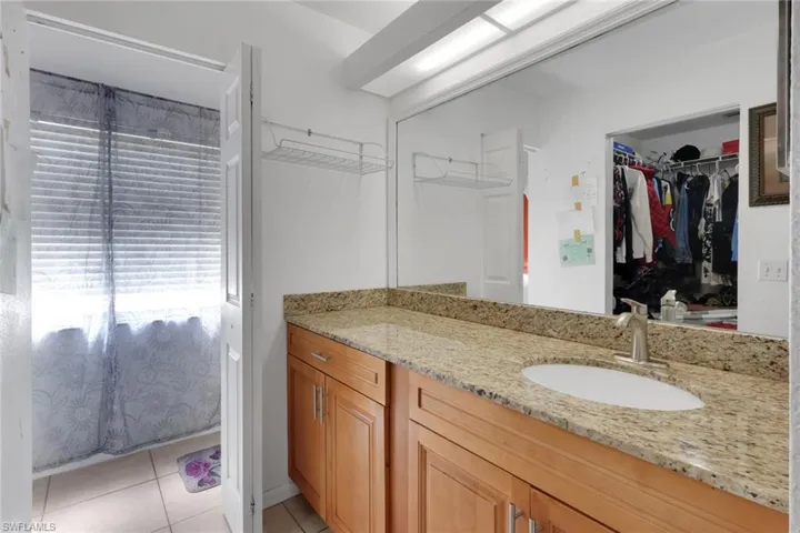 Ensuite bathroom with vanity, light tile patterned floors, and a walk in closet