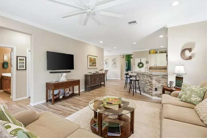 Open concept living area featuring wood-finish flooring, crown molding, and recessed lighting