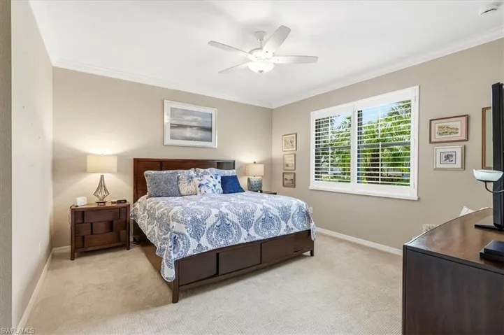 Carpeted room featuring a ceiling fan, crown molding, a window with plantation shutters, and neutral wall tones
