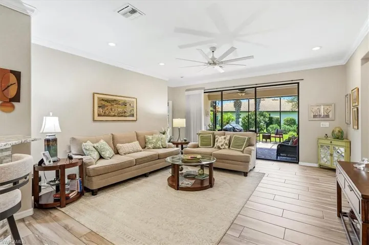 Spacious living area featuring wood-finish flooring, crown molding, and a large ceiling fan