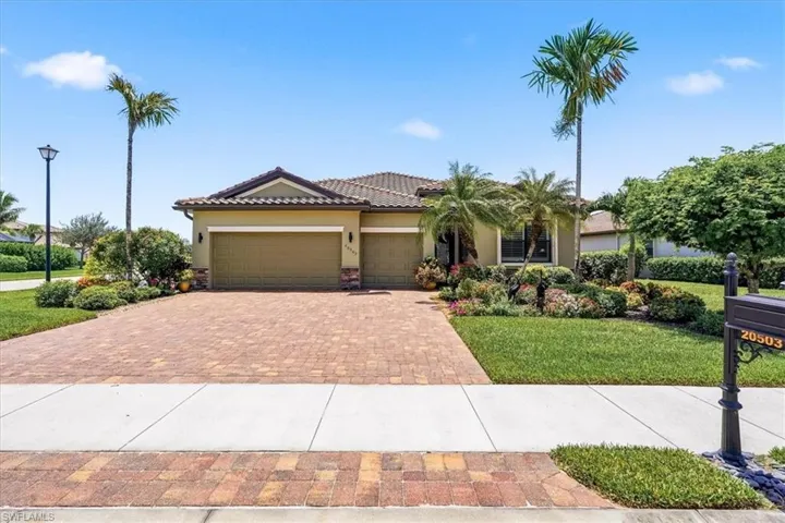 Exterior featuring a paver driveway, two-car garage, Mediterranean tile roof, and mature palm trees
