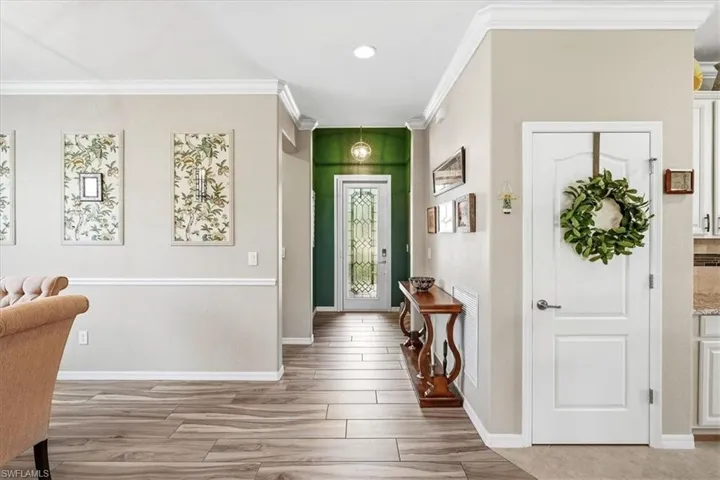 Entryway featuring wood-finish tile flooring, crown molding, and wainscoting