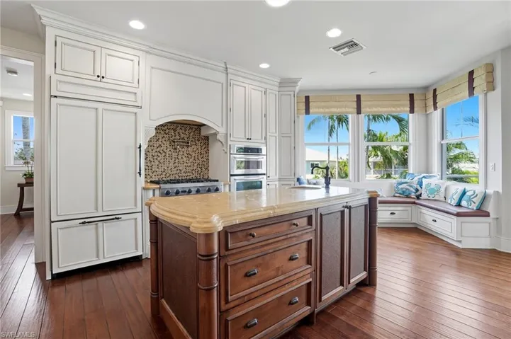 Kitchen with white cabinets, dark wood finished floors, a center island, recessed lighting, and light stone countertops - Virtually Edited Image