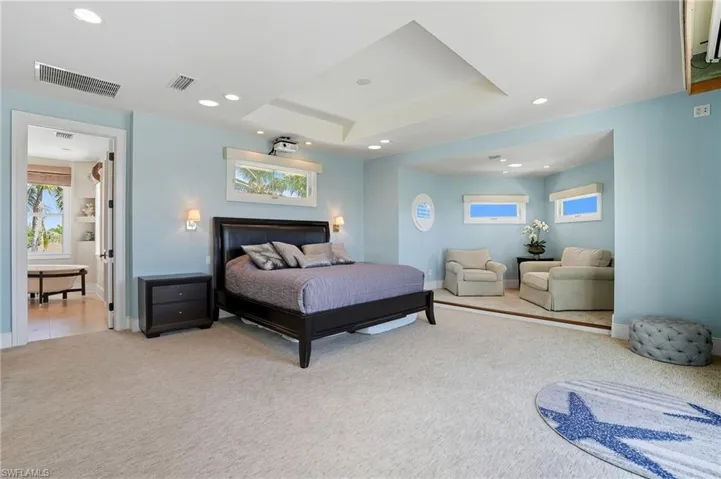 Bedroom featuring multiple windows, light colored carpet, recessed lighting, and a tray ceiling - Virtually Edited Image