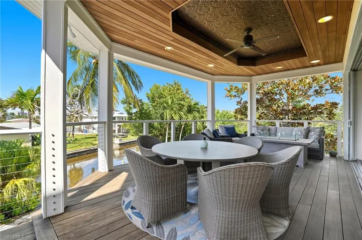 Sunroom featuring outdoor dining area, ceiling fan, and a wooden deck - Virtually Edited Image