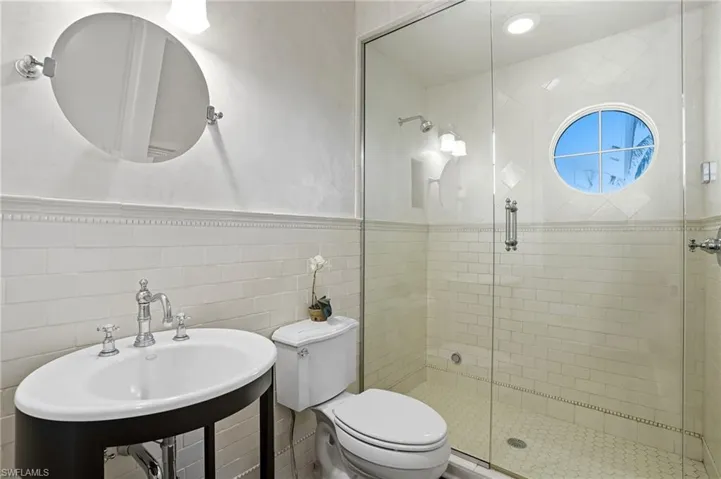 Full bathroom with a shower stall, tile walls, and a wainscoted wall - Virtually Edited Image
