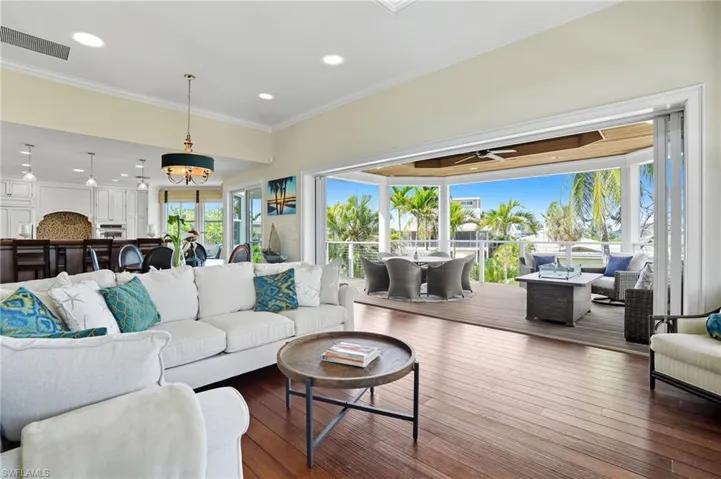Living room featuring hardwood / wood-style floors, recessed lighting, and crown molding - Virtually Edited Image