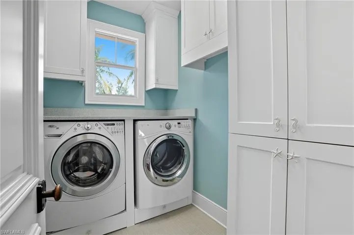 Laundry area featuring cabinet space, washer and dryer, and light tile patterned floors