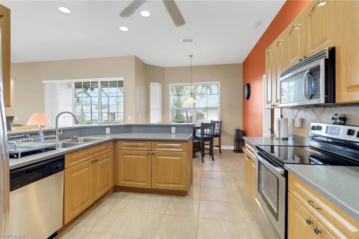 Kitchen featuring appliances with stainless steel finishes, tasteful backsplash, light tile patterned flooring, a ceiling fan, and hanging light fixtures