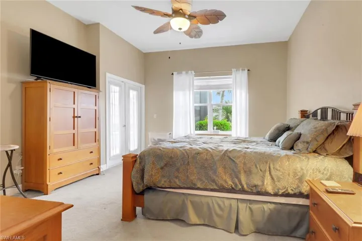 Bedroom with light colored carpet and a ceiling fan
