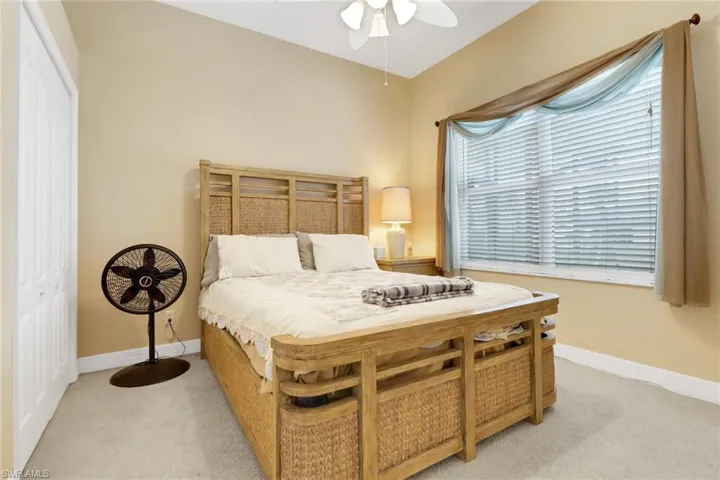 Bedroom with light colored carpet, ceiling fan, and a closet