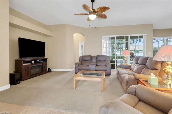 Carpeted living area featuring arched walkways and ceiling fan