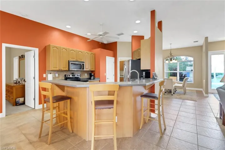 Kitchen featuring stainless steel appliances, decorative backsplash, a kitchen bar, a peninsula, and a chandelier