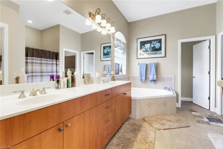 Full bath with double vanity, a garden tub, tile patterned floors, and a shower with curtain