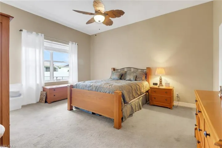 Bedroom with light carpet and a ceiling fan