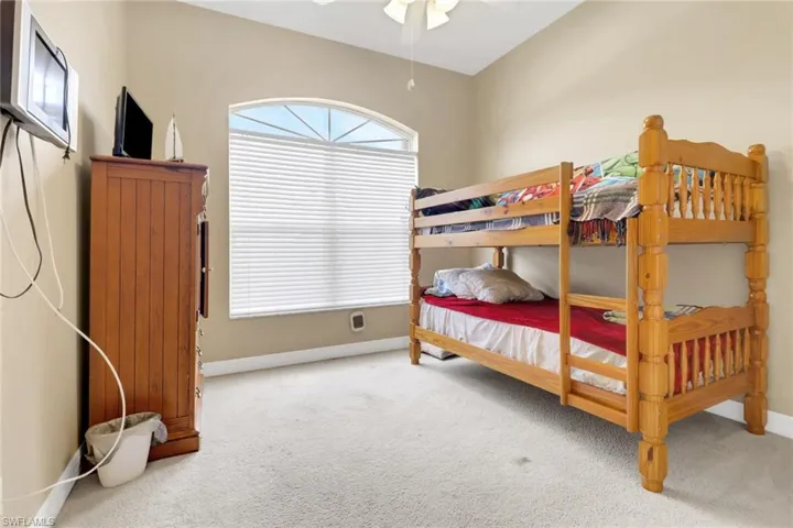 Carpeted bedroom featuring multiple windows and a ceiling fan