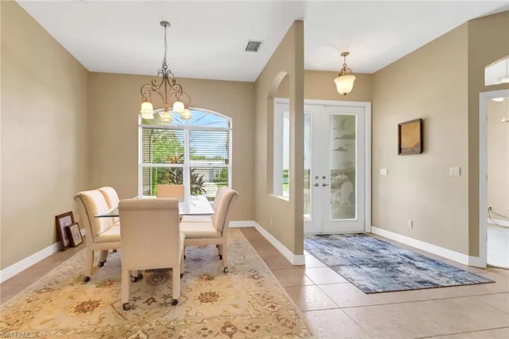 Dining room featuring a chandelier, light tile patterned flooring, french doors, and arched walkways