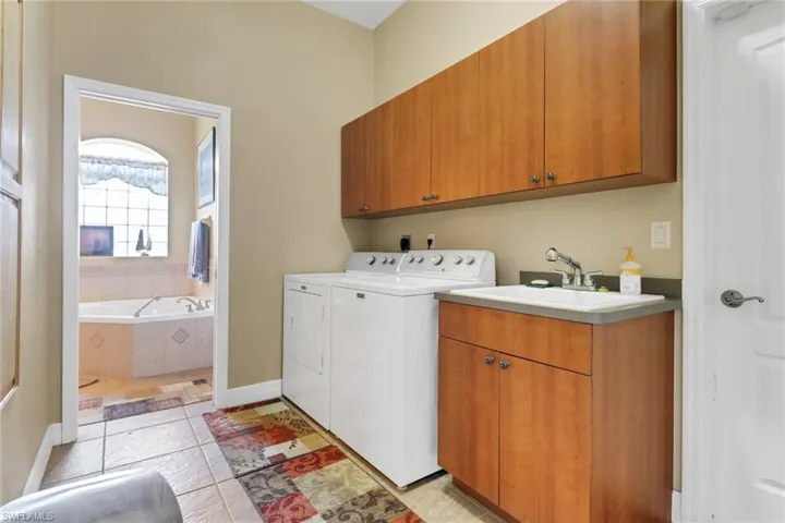 Washroom with cabinet space, independent washer and dryer, and light tile patterned floors