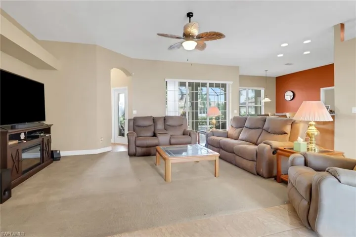 Living room featuring a ceiling fan, arched walkways, recessed lighting, and light colored carpet
