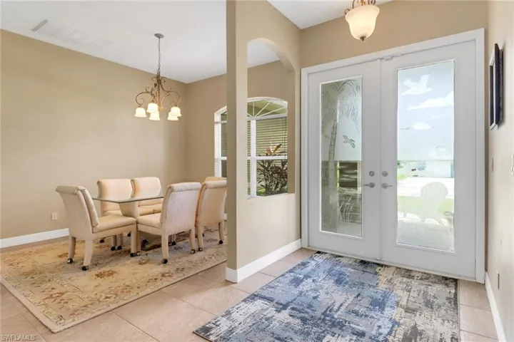 Dining room featuring a chandelier, light tile patterned flooring, french doors, and arched walkways