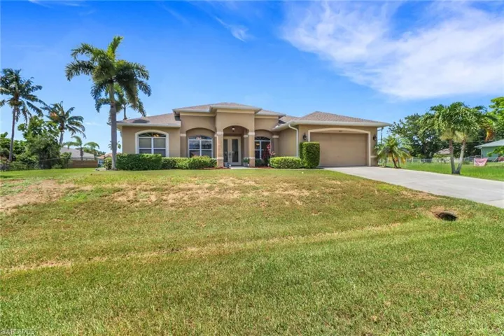Mediterranean / spanish home with stucco siding, driveway, an attached garage, a front lawn, and french doors