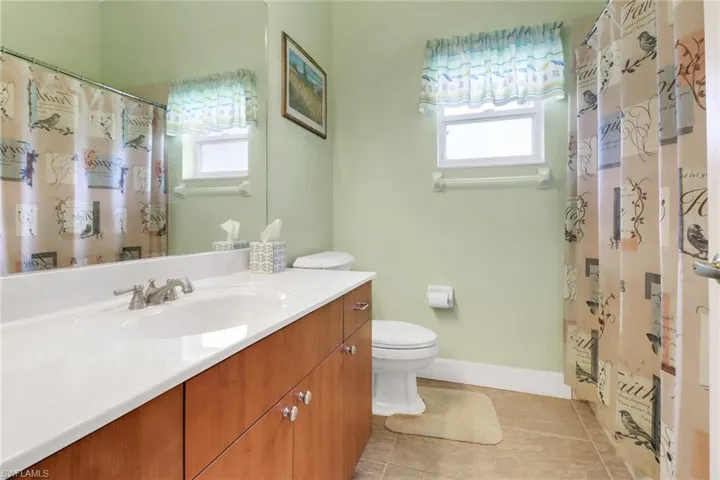 Full bath with vanity, plenty of natural light, tile patterned floors, and curtained shower