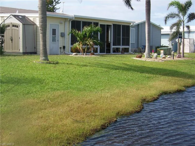 Located on large pond, back showing HUGE all weather Florida room with shed and gardens.