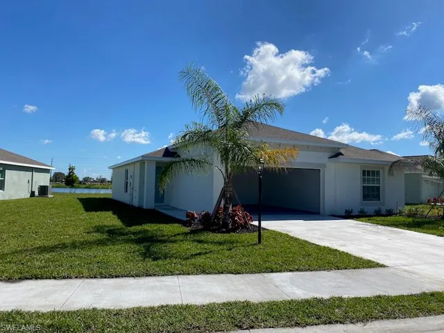 View of front of house with an attached garage, a front lawn, concrete driveway, and stucco siding