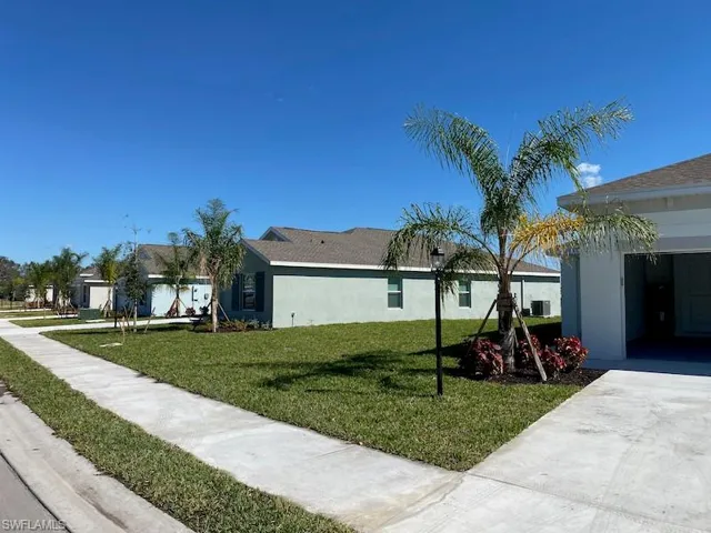 View of side of property with a yard, stucco siding, and a residential view