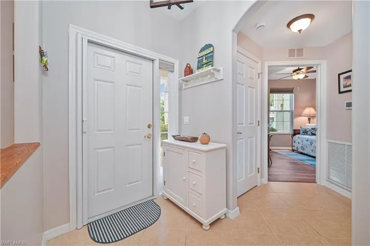 Foyer featuring arched walkways, light tile patterned floors, and ceiling fan