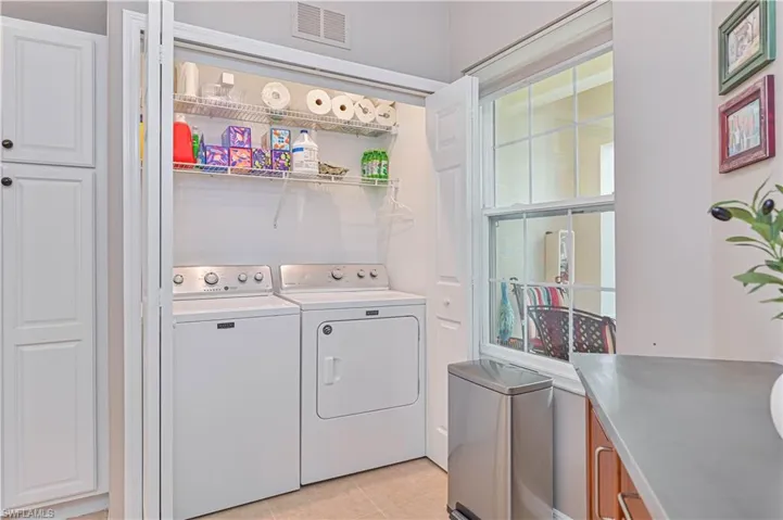 Washroom with light tile patterned floors and washer and dryer