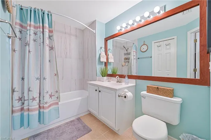 Full bathroom with shower / bath combo with shower curtain, vanity, and light tile patterned flooring